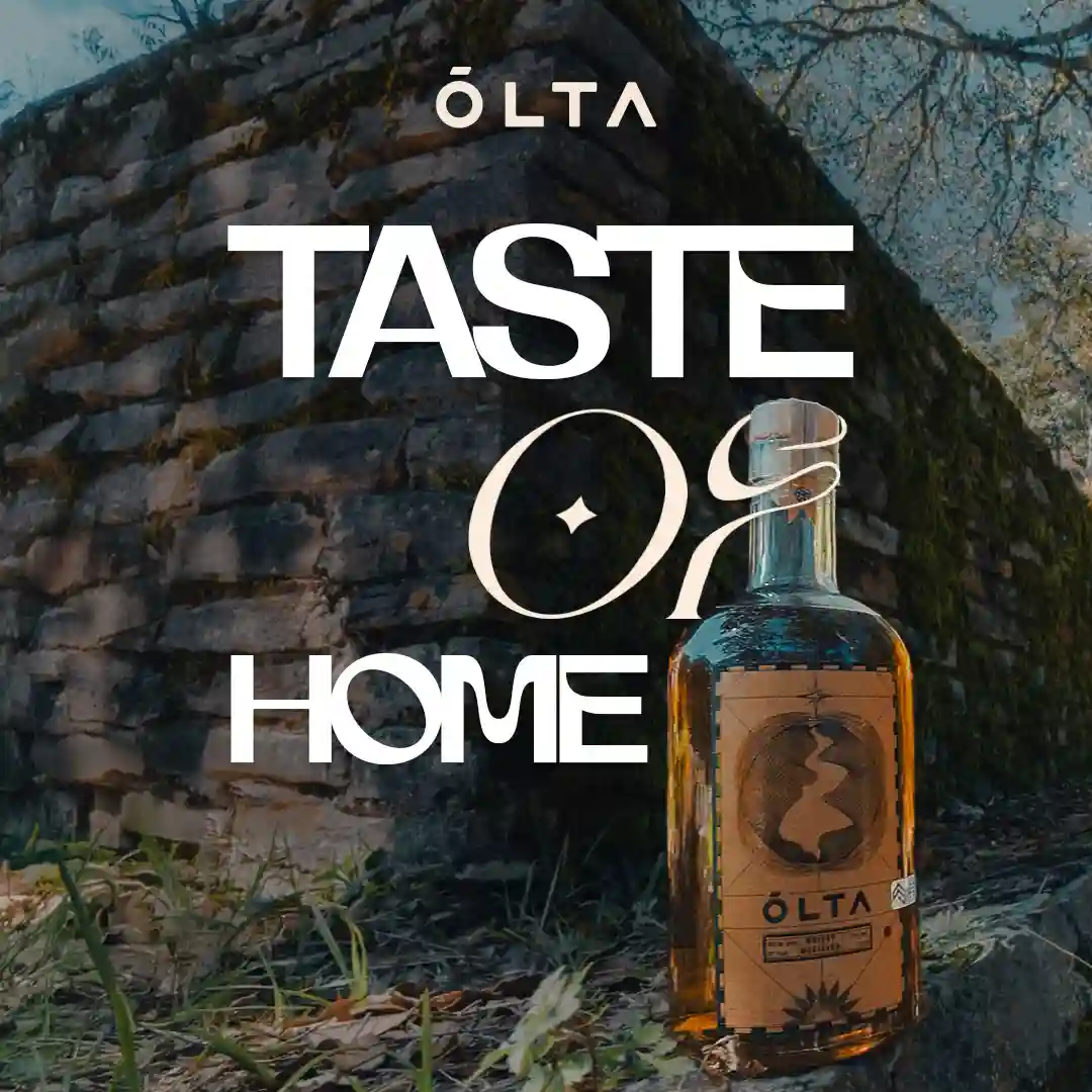 ÓLTA bottle against rustic stone wall with dramatic lighting